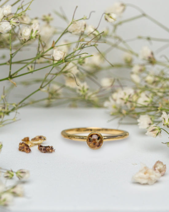 A gold ring with umbilical cord surrounded by baby's breath flowers