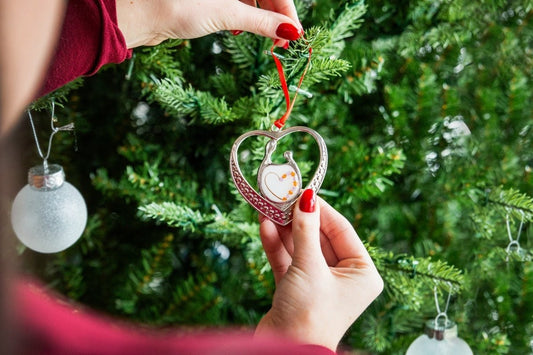 Unbreakable Bond Ornament hanging on a Christmas tree with red ribbon and breastmilk heart design