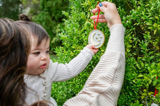 Baby reaching for the My Moon and Stars breastmilk keepsake ornament outdoors.