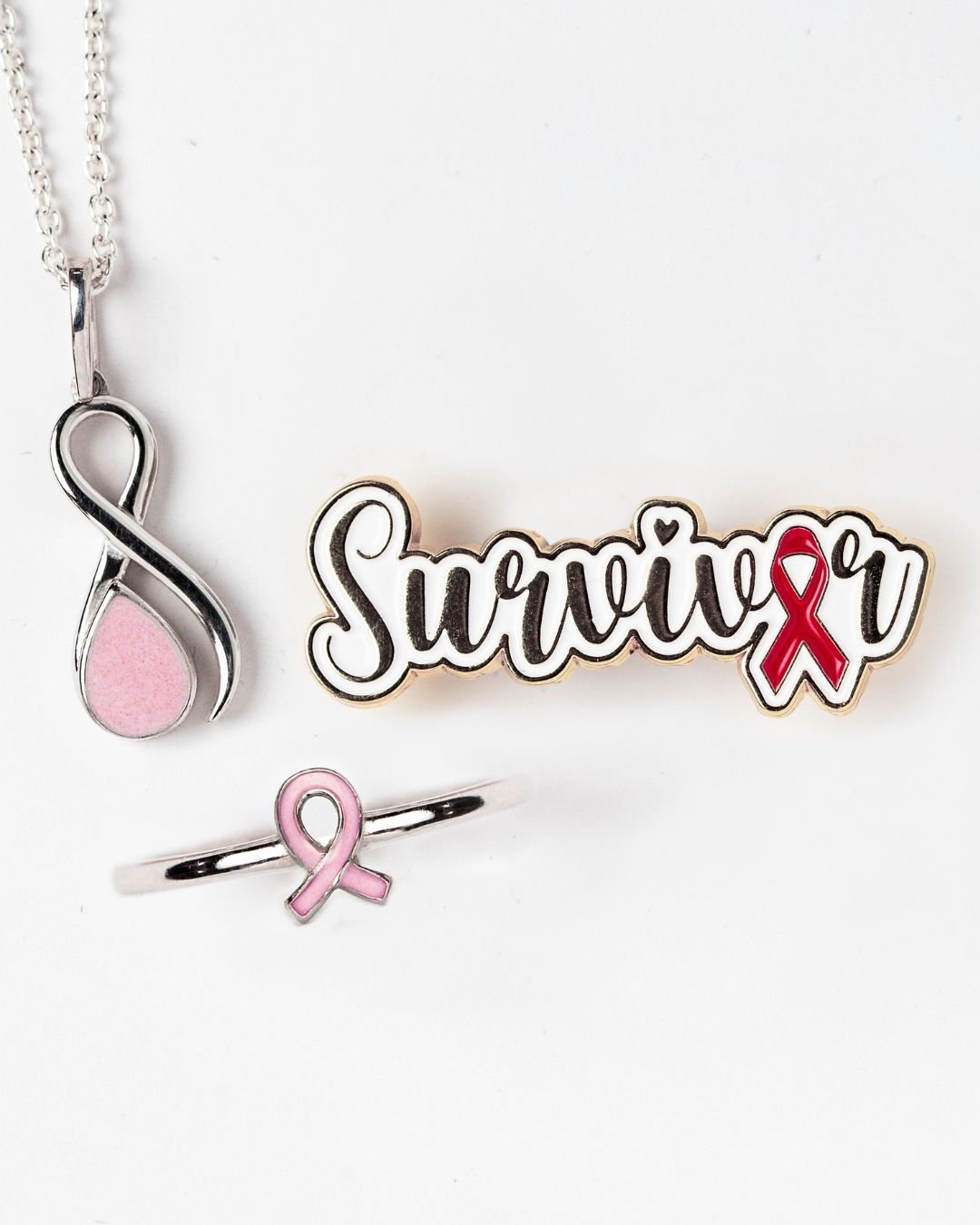 Pink ribbon keepsake jewelry beside survivor ribbon enamel pin