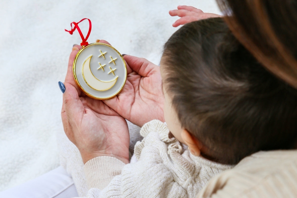 Mother holding the My Moon and Stars ornament with a baby in her lap.