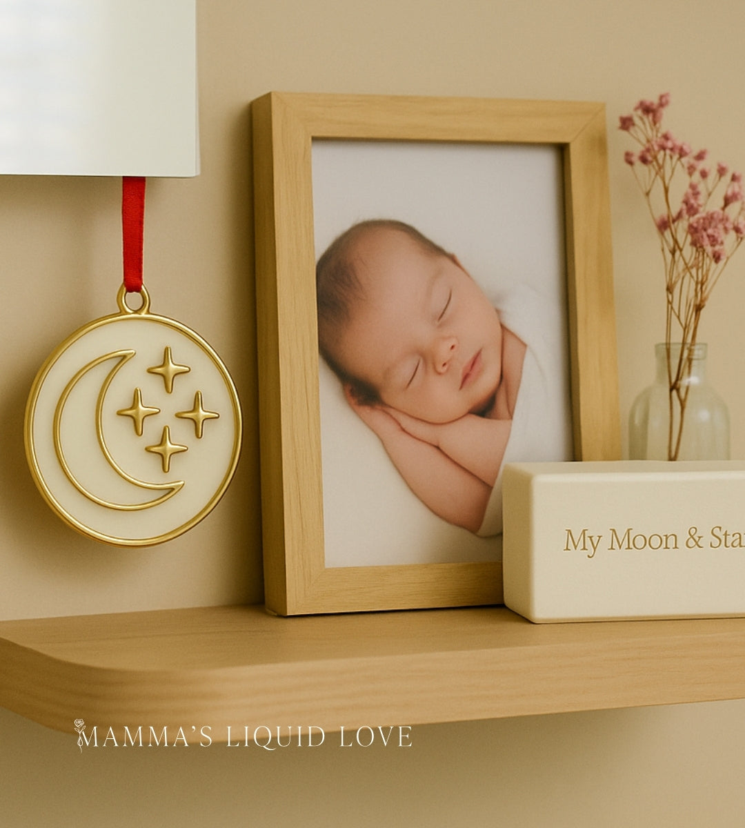 My Moon and Stars Breastmilk Keepsake Ornament by Mamma’s Liquid Love displayed on a nursery shelf with a baby photo.
