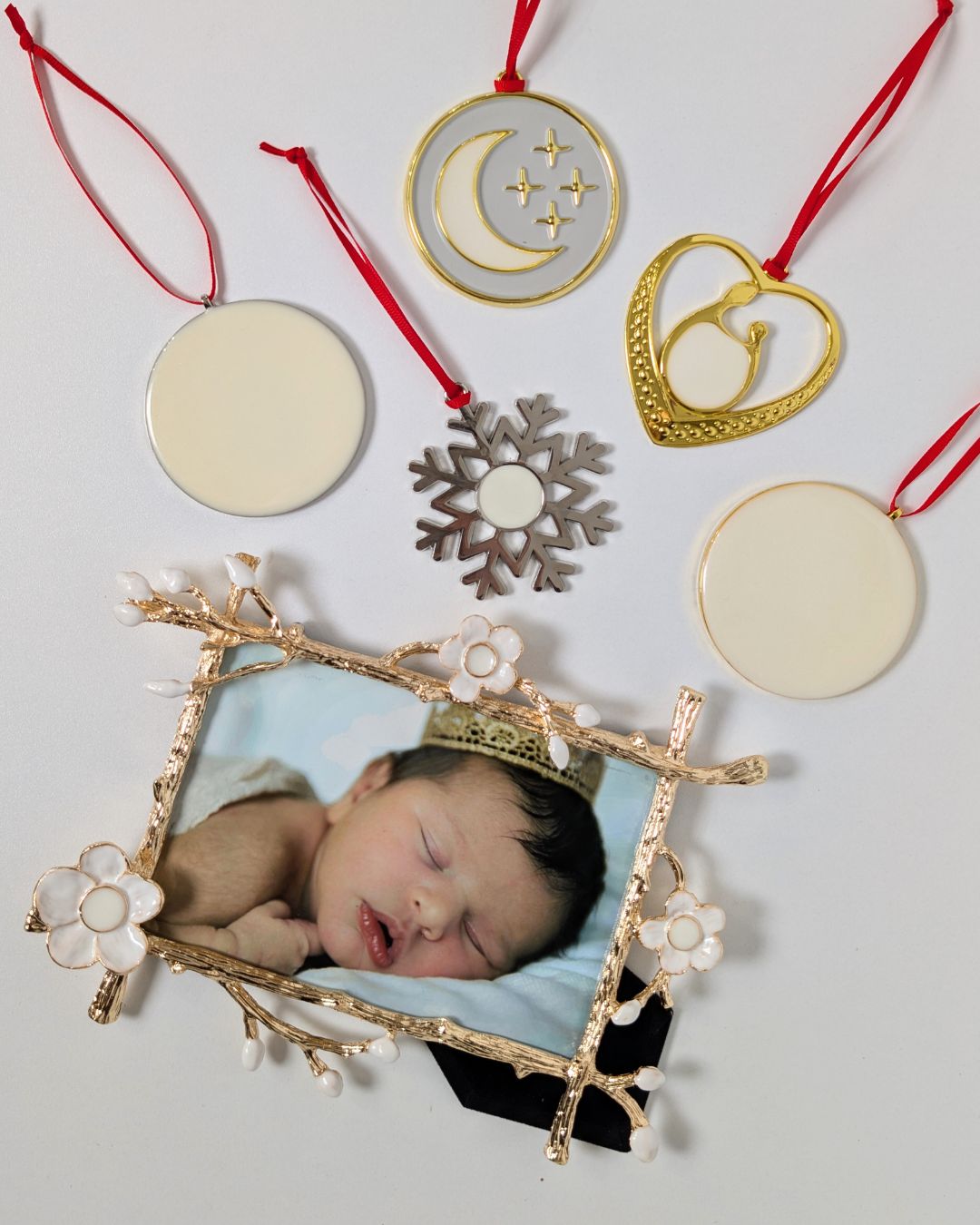 Flatlay of Mamma’s Liquid Love Ultimate Keepsake Bundle showing a gold floral frame with a baby photo and multiple breastmilk ornaments in heart, moon, snowflake, and round designs.